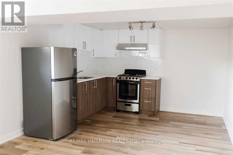 A kitchen with a refrigerator, oven, and cabinets.
