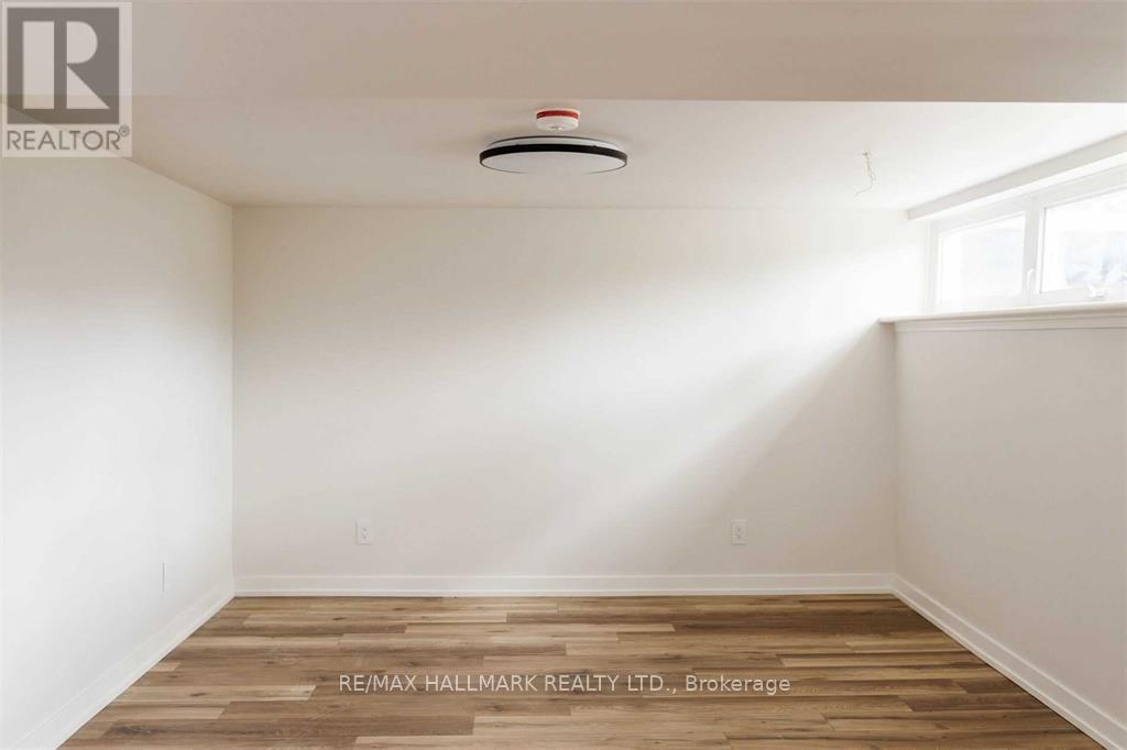 A room with a wooden floor and a smoke detector on the ceiling.