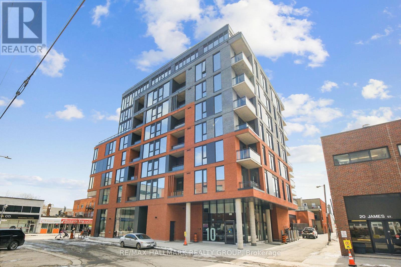 A modern multi-story building with a red brick facade and large windows.