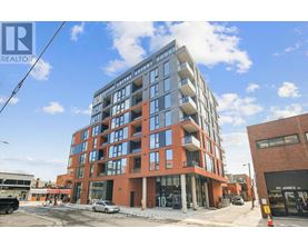 A modern multi-story building with a red brick facade and large windows.