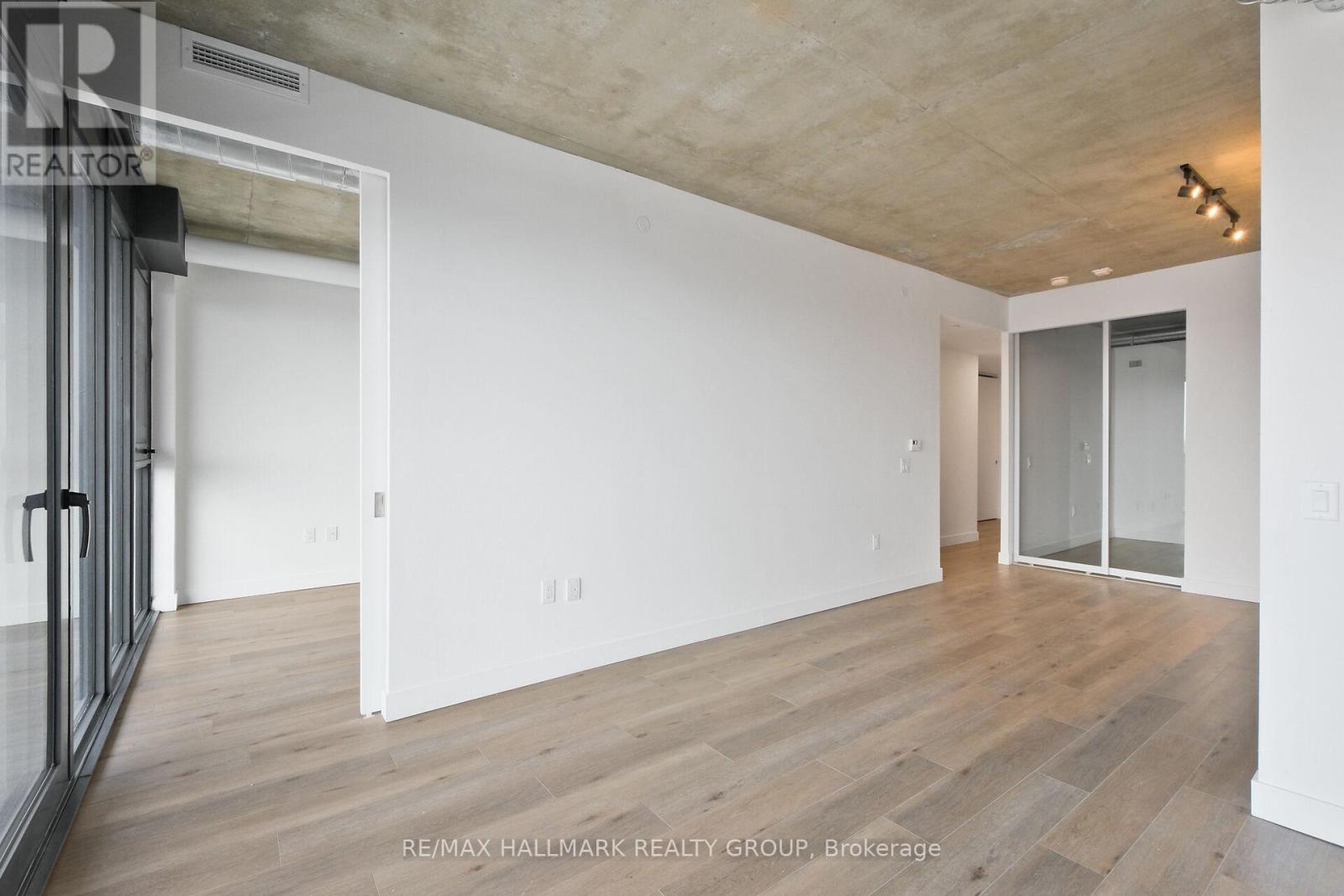 A spacious room with wooden flooring and white walls.