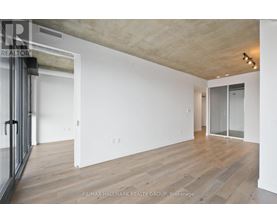 A spacious room with wooden flooring and white walls.