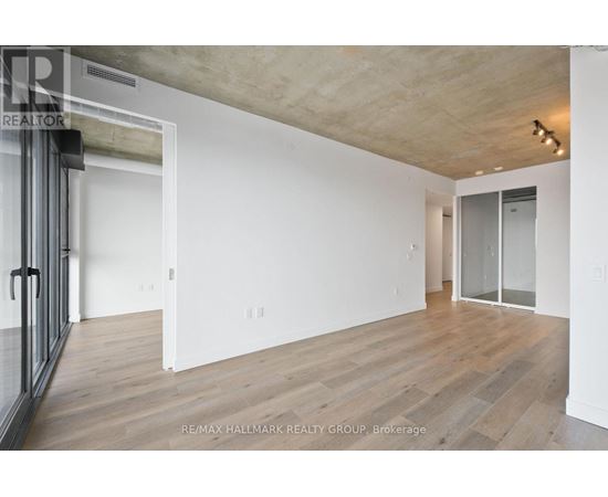 A spacious room with wooden flooring and white walls.