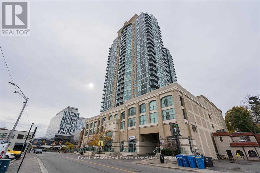 A tall building with a glass facade stands next to a shorter building with a beige facade.