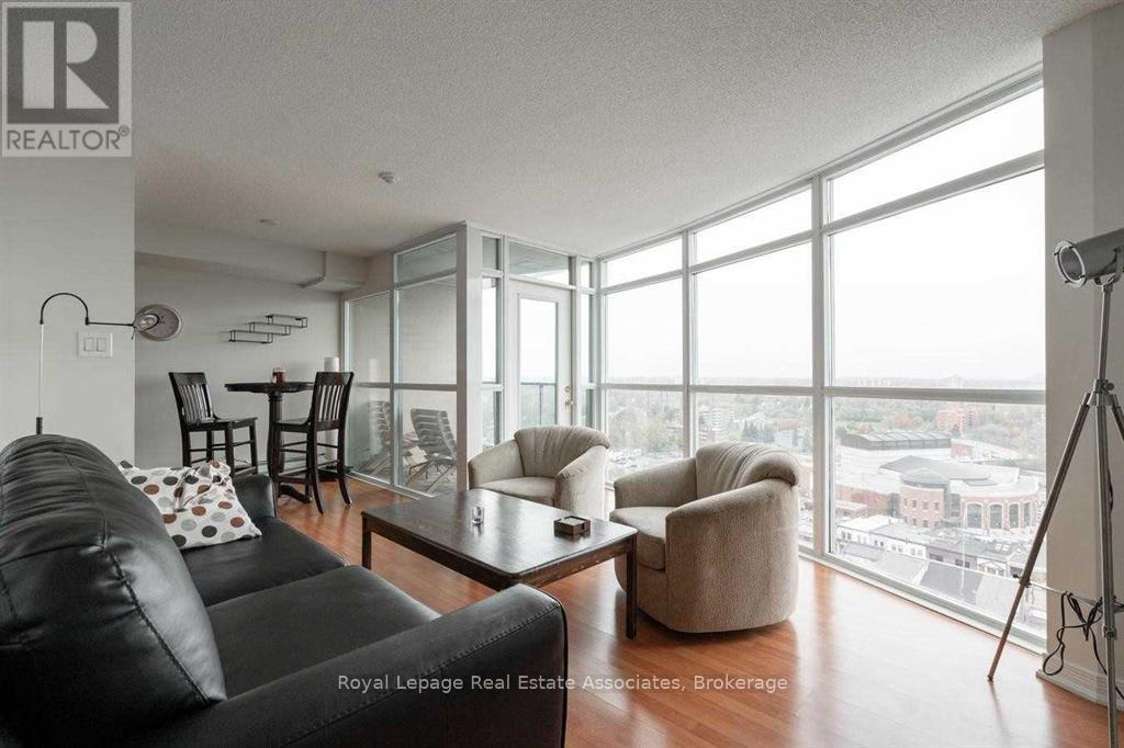 A living room with a black couch and a large window overlooking the city.