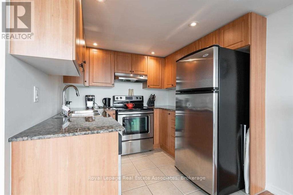 A kitchen with a black refrigerator and wooden cabinets.