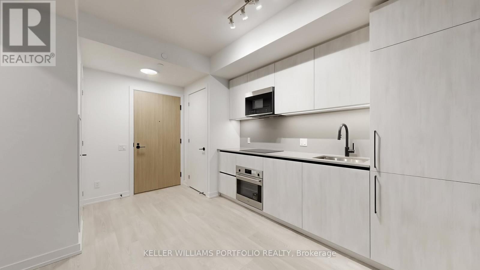 A kitchen with white cabinets and a microwave above the oven.