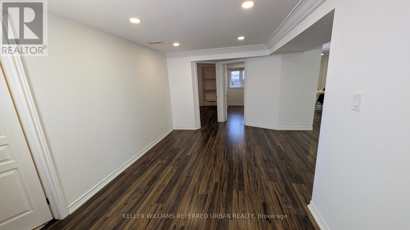 A spacious room with wooden flooring and white walls.