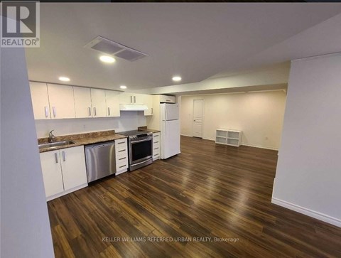 A kitchen with white cabinets and a wooden floor.
