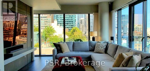 A living room with a grey couch and a red coffee table.