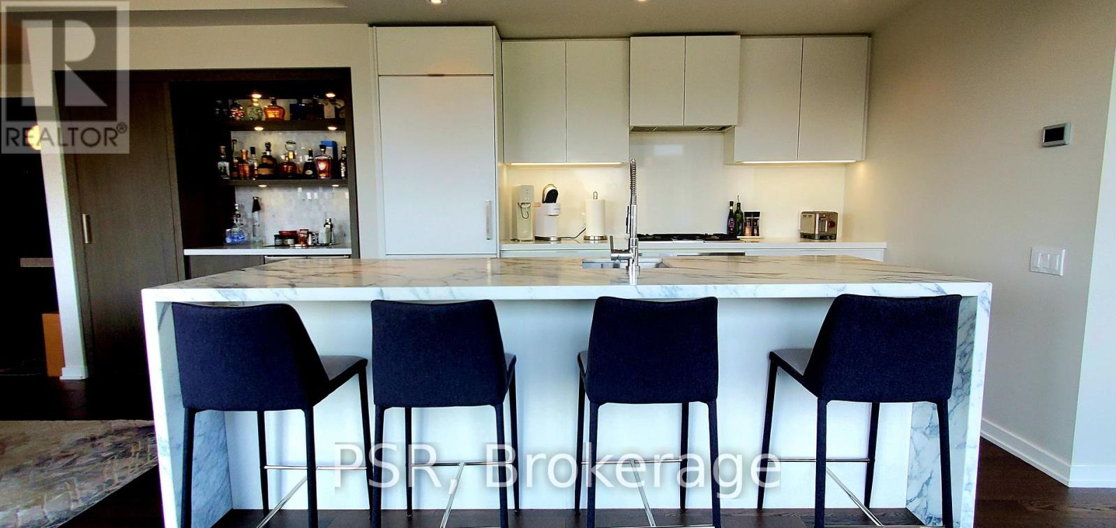 A kitchen with a bar stool in front of it.