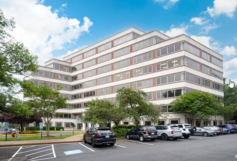 A large multi-story building with a parking lot in front.