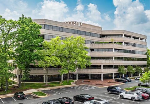 A large, modern building with a parking lot in front.