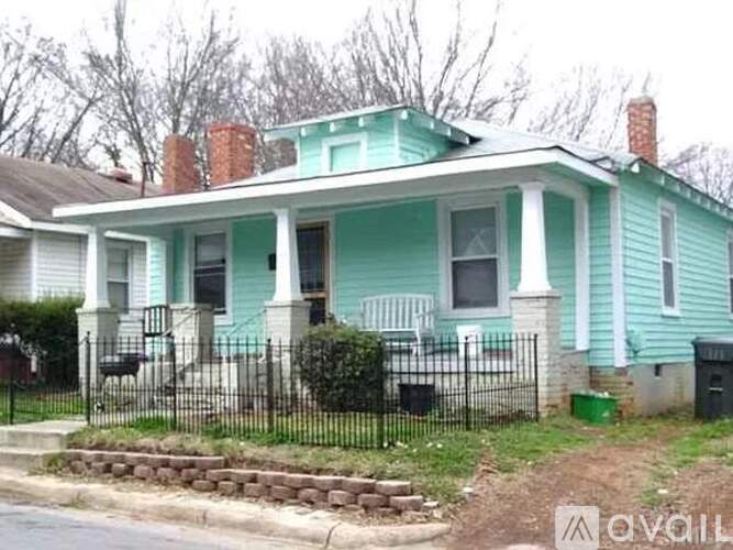 A blue house with a white porch and a black fence.