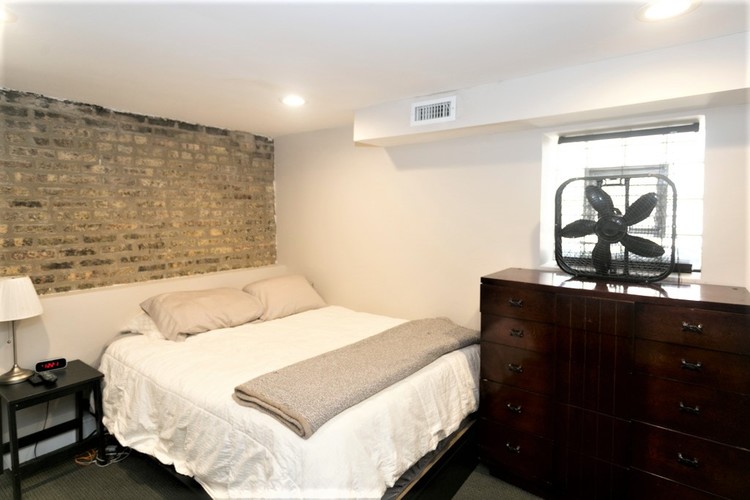 A bedroom with a brick wall behind the bed.
