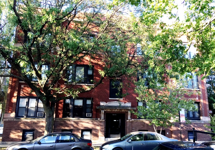 A red brick building with a tree in front of it.