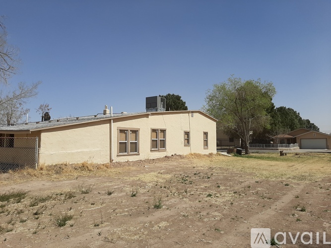 A house with a fence and a tree in front of it.