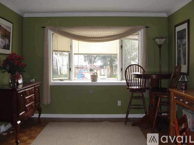 A room with green walls and a window with a view of trees and a house.