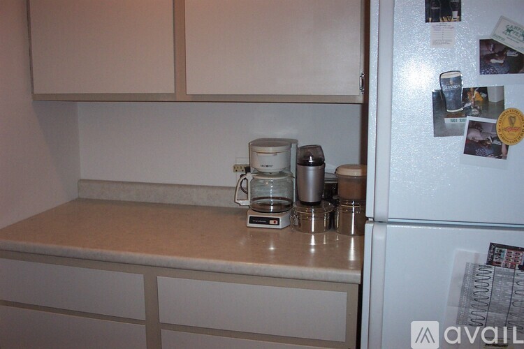 A kitchen with a white fridge and a counter with a coffee maker and a jar on it.