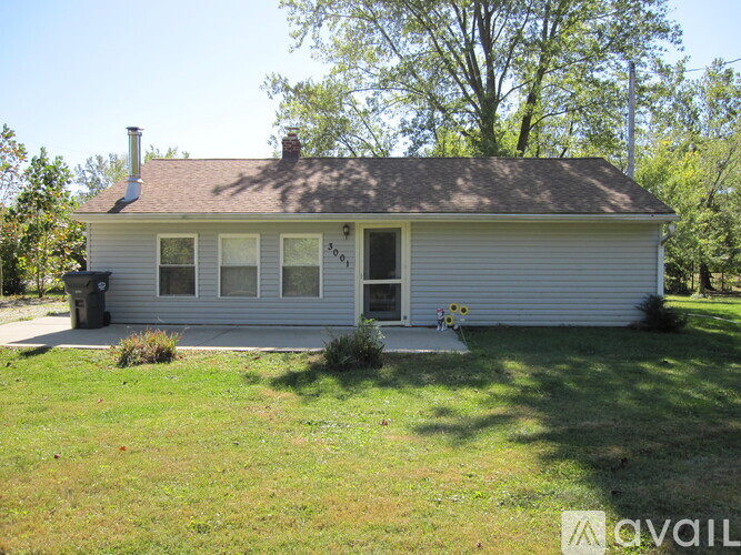 A small house with a white front porch and a mailbox on the right side.