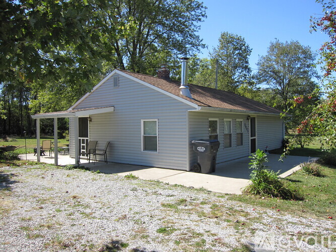 A small house with a porch and a trash can.