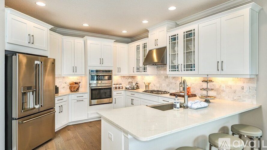 A modern kitchen with white cabinets and stainless steel appliances.