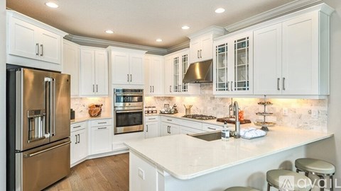 A modern kitchen with white cabinets and stainless steel appliances.