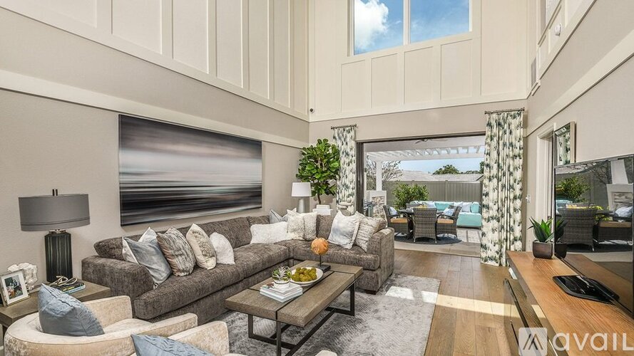 A living room with a large couch, a coffee table, and a large window with a view of the ocean.