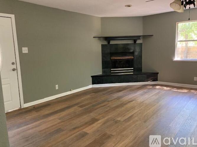A living room with a fireplace and wood flooring.