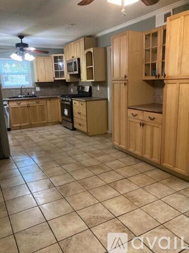 A kitchen with wooden cabinets and tile flooring.