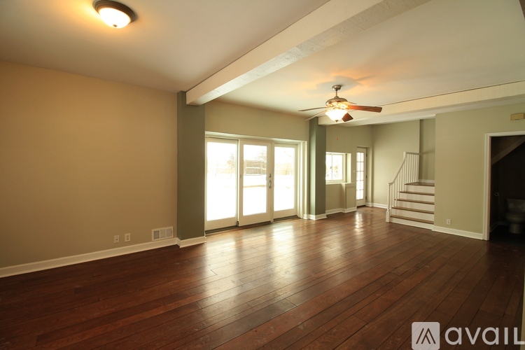 A spacious room with wooden floors and a ceiling fan.