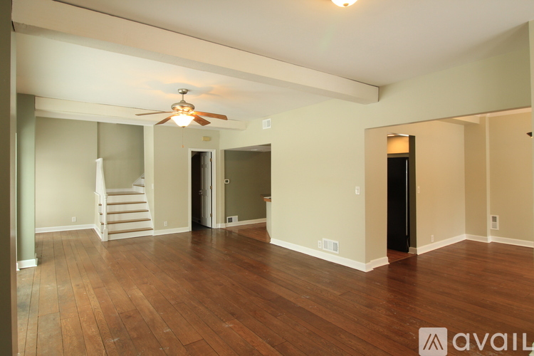 A spacious room with wood flooring and a ceiling fan.