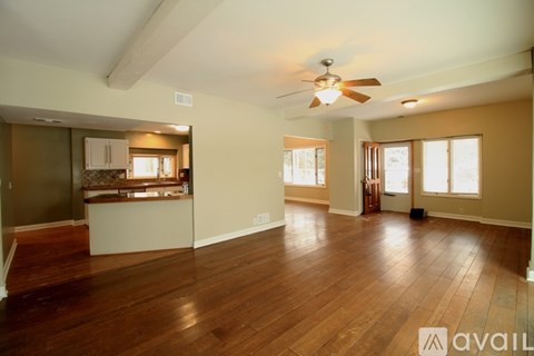 A spacious living room with wood flooring and a ceiling fan.