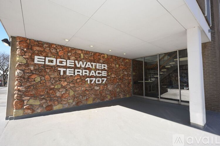 A building with a stone wall and glass doors is labeled Edge Water Terrace 1707.