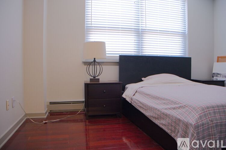 A bedroom with a bed, nightstand, and window with blinds.