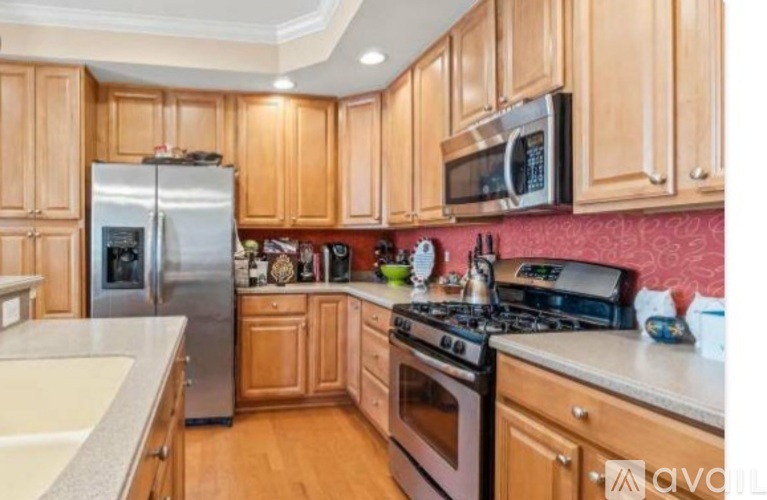 A kitchen with wooden cabinets and a stainless steel refrigerator.