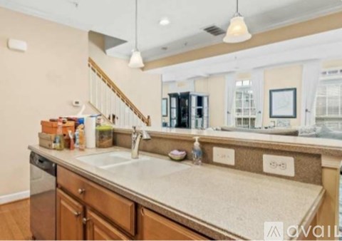 A kitchen with a sink and a staircase in the background.