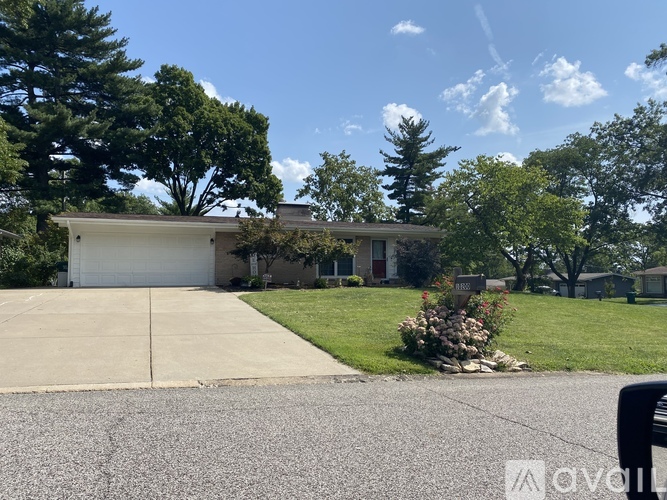 A house with a driveway and trees in the background.
