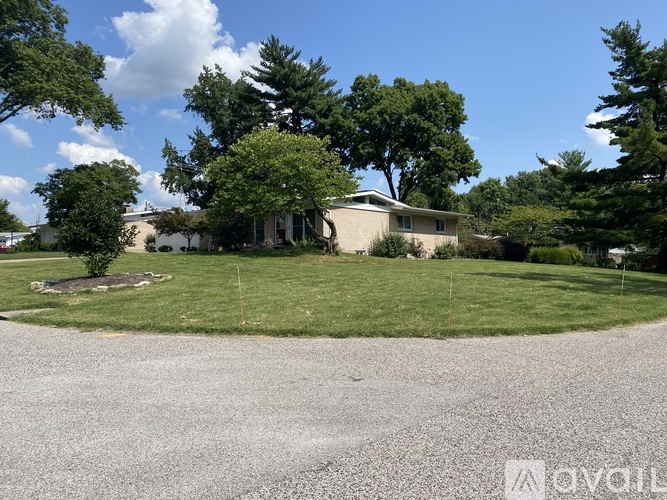 A house with a gravel driveway and trees in the background.