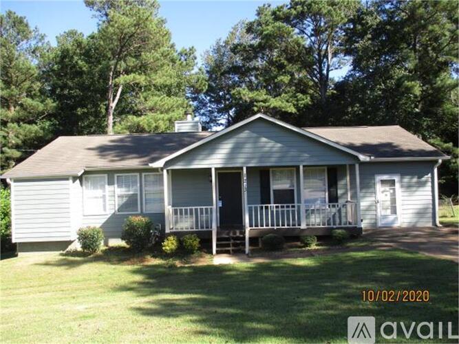 A house with a porch and a tree in the background.