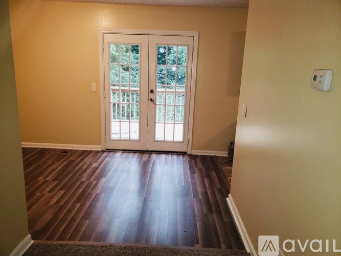A room with a white door and wooden flooring.