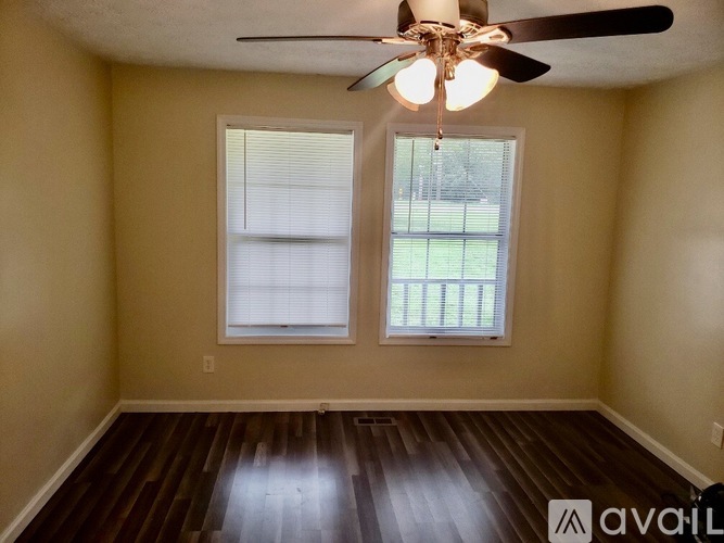 A room with a ceiling fan and two windows.