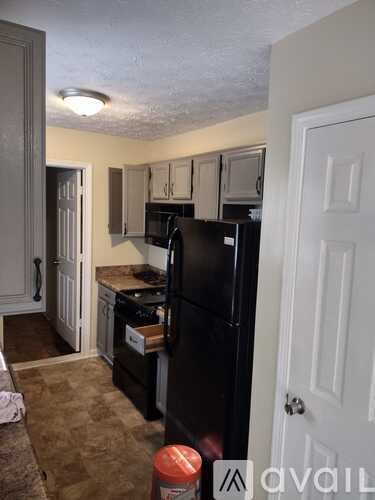 A kitchen with a black refrigerator and white cabinets.