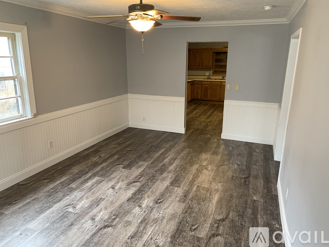 A room with a ceiling fan and wood flooring.