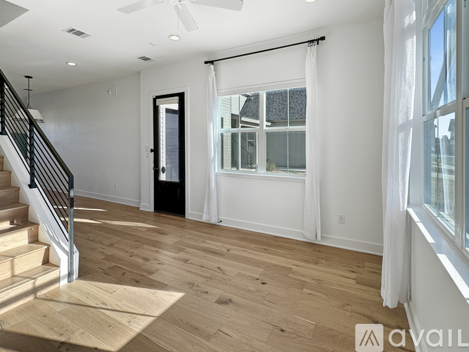 A spacious room with wooden flooring and a staircase leading to the upper level.