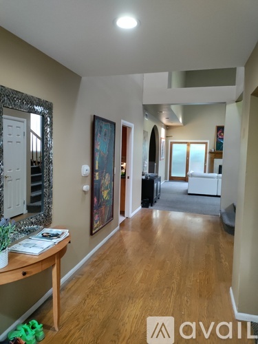 A hallway with a wooden floor and a mirror on the left side.