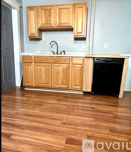 A kitchen with wooden cabinets and a black dishwasher.