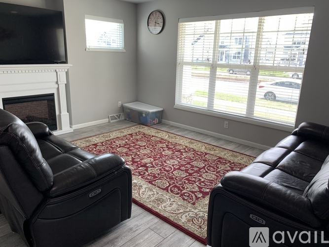 A living room with two black leather sofas and a fireplace.