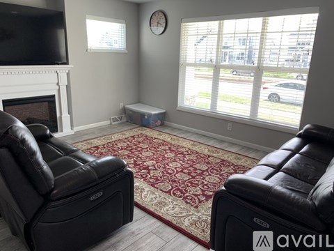 A living room with two black leather sofas and a fireplace.