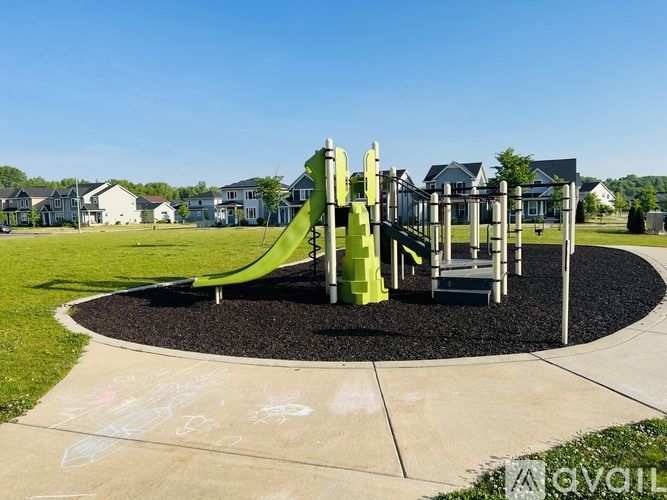 A playground with a green slide and a grey ground.
